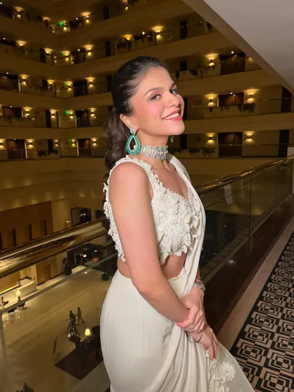 The pop of color from the emerald earrings contrasts beautifully with the all-white saree and the fresh, glowing makeup.