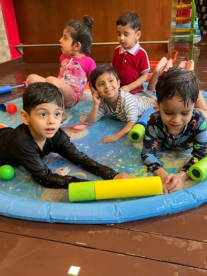 A group of friends enjoying some downtime on the splash mat with water squirters. These moments of shared play are so important for social development.