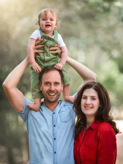 An outdoor family portrait doesn't always have to be formal. This shot captures a happy, relaxed family enjoying a moment together in nature, with their son perched happily on his father's shoulders.