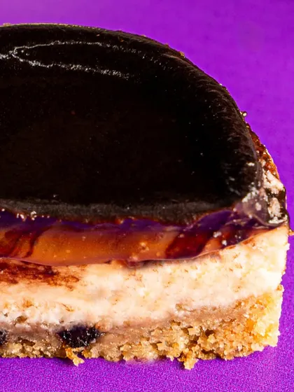 A close-up of the Bebe Frank, our new single-serve version of the classic. You can see the distinct layers of cookie base, creamy cheesecake, and caramel, all waiting to be topped with our signature ganache.