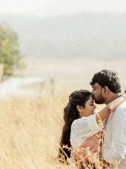 A gentle and romantic portrait of a forehead kiss in a golden field, capturing a moment of pure affection.