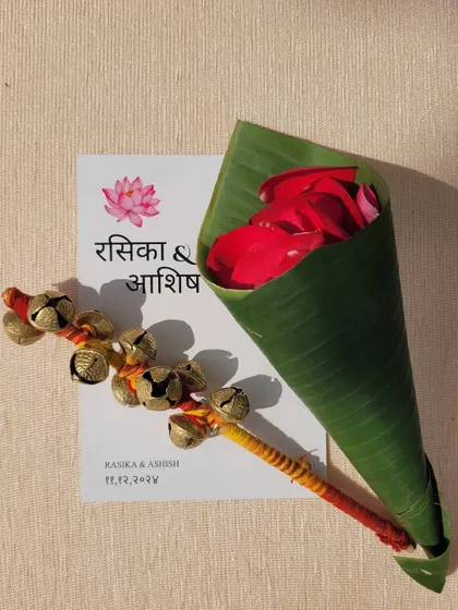 Personalized wedding stationery paired with traditional elements like ghungroos and a cone of rose petals for showering the couple.