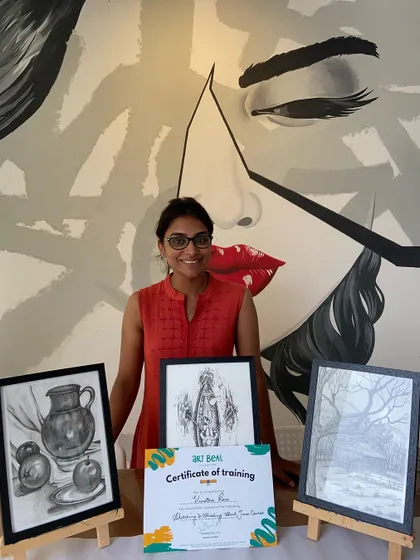A proud student poses with her certificate and three detailed sketches. The studio's iconic mural makes for a great photo backdrop.