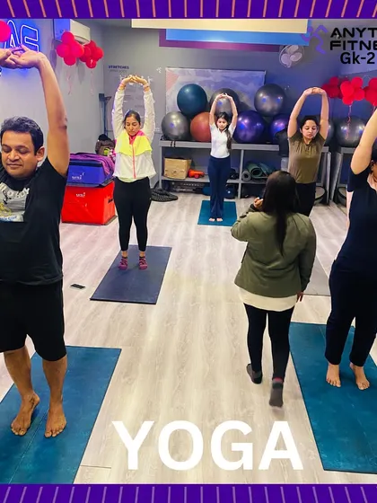 A group of members practicing a standing stretch during a yoga class. The focus and dedication are clear, highlighting the mindful aspect of our yoga sadhana.