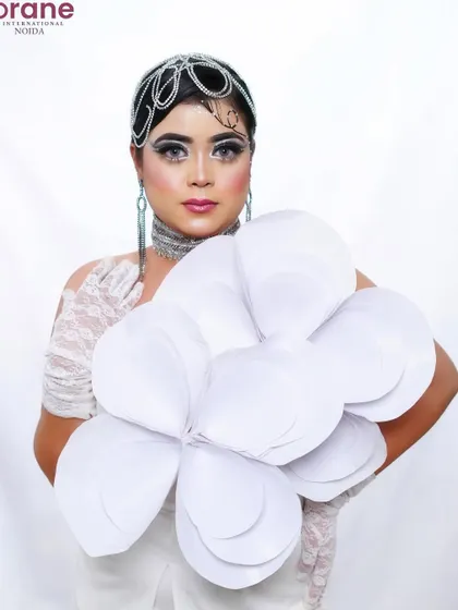 The use of a large, paper flower as a prop adds a surreal and artistic element to the shoot.