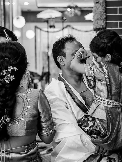A playful, candid moment between a father and daughter during the wedding rituals, captured in timeless black and white.