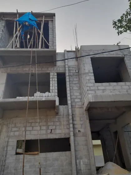 Progress shot of 'Nidhi Nilayam'. This low-angle view emphasizes the verticality of the structure and the interplay between the different floor levels and cantilevered sections, which are key features of the design.