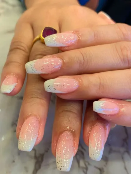 A classic ombre design with a twist. These square-shaped nails feature a pink-to-white fade, enhanced with a light dusting of fine silver glitter for a shimmering finish.
