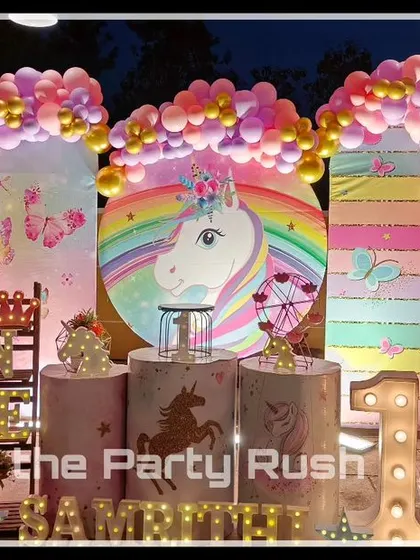 Samrithi's first birthday was a vibrant unicorn-themed celebration. This outdoor setup features multiple balloon arches, a large unicorn backdrop, and characters from My Little Pony, creating a colorful and magical party scene.