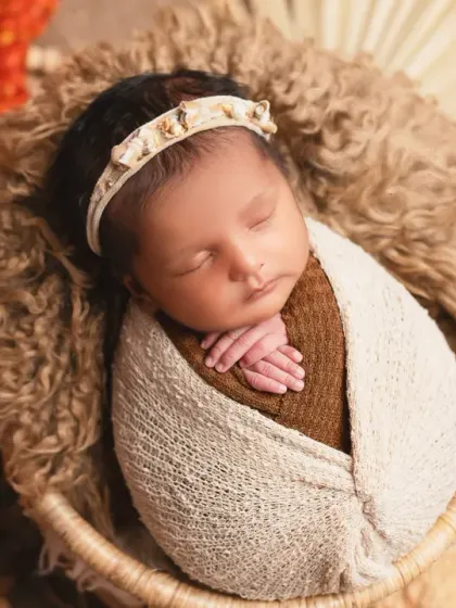 A close-up of a newborn swaddled snugly in a basket, showcasing a bohemian-inspired style with earthy tones and natural textures. This is a popular style for modern newborn photography.