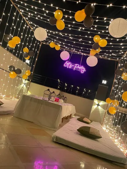 A different perspective of the nighttime terrace party, showing the full extent of the fairy light canopy and seating arrangement.