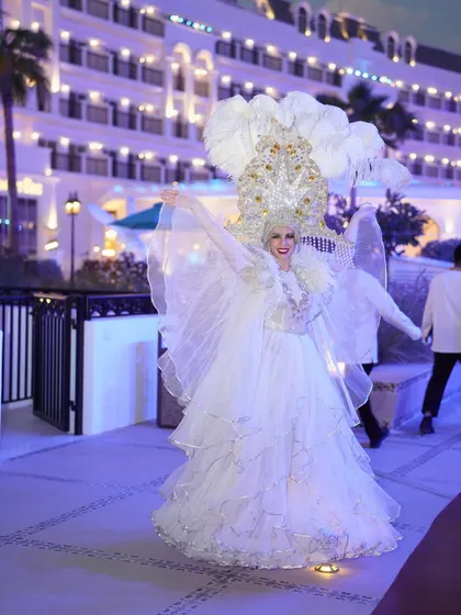 A performer in an angelic, illuminated white costume with large feathered wings, greeting guests and adding a touch of ethereal magic to the evening.