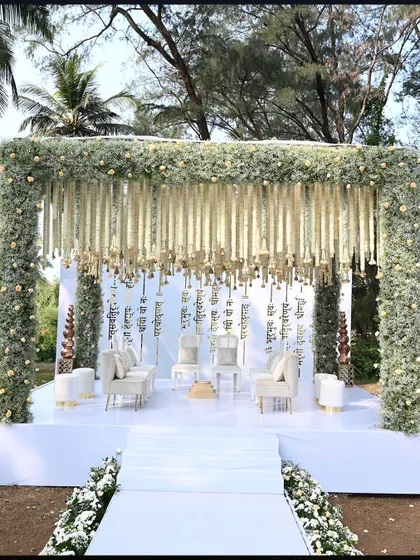 A detailed look at the pristine white mandap at ITC Goa, framed by lush greenery. The hanging floral strings and clean white stage create a heavenly atmosphere.