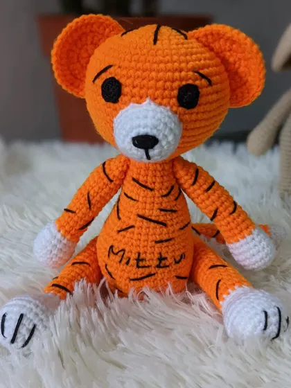 The custom-named tiger 'Mittu' sitting on a soft white surface, ready for cuddles.