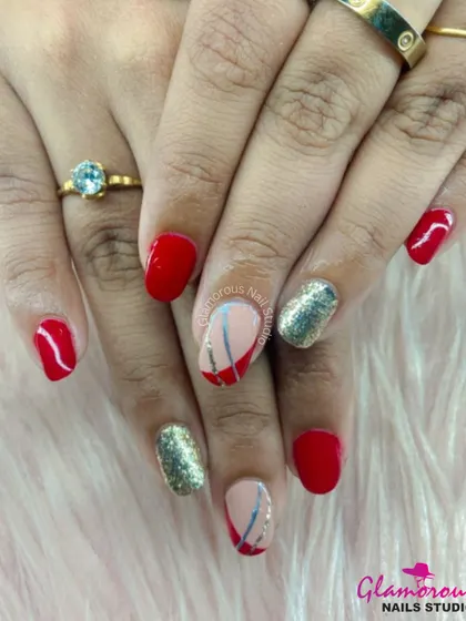 This design pairs classic red nails with full-coverage gold glitter accent nails and abstract line art for a modern, edgy look.