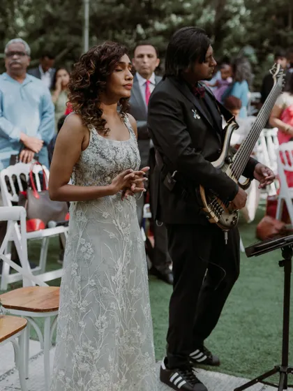 The bride and groom, who are also musicians, stand together during their ceremony, with the groom holding his bass guitar. I help couples weave their passions into their wedding day.