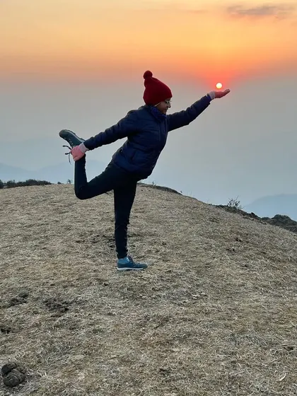 Holding Natarajasana, the lord of the dance pose, as the sun sets over the mountains during a trek. This pose is a beautiful expression of balance and grace, and practicing it in nature's embrace brings a profound sense of peace and connection to the end of the day.