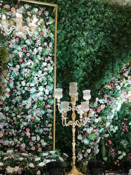 A breathtaking reception stage where a wall of lush greenery is densely packed with a variety of pastel flowers. This design creates the feel of an enchanted garden, complete with elegant candelabras and chandeliers.