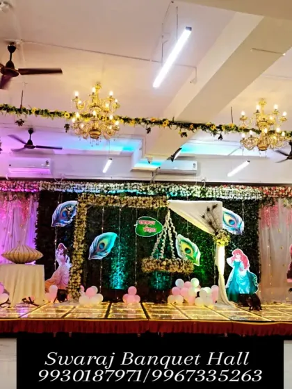 A wide shot of a naming ceremony setup in our banquet hall, featuring a green foliage backdrop and peacock feather details. This versatile decoration can be customized for a baby boy or girl.