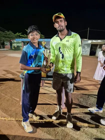 A coach presenting the Player of the Match trophy to Arya Ayyappan for his brilliant 3-wicket spell in the U-14 Kreeda Macushla Cricket Carnival final.