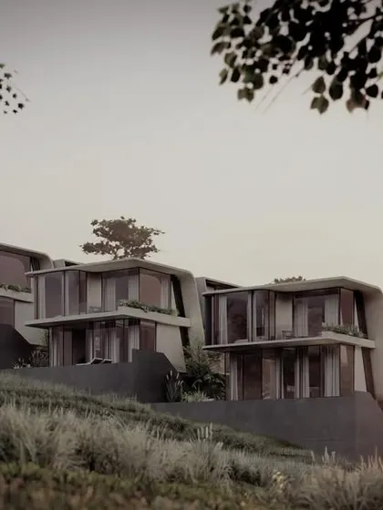 The Moira Homes at dusk, where the architectural forms are silhouetted against the sky. The design works with the natural slope, creating a mix of apartments and homes that feel grounded in their environment.