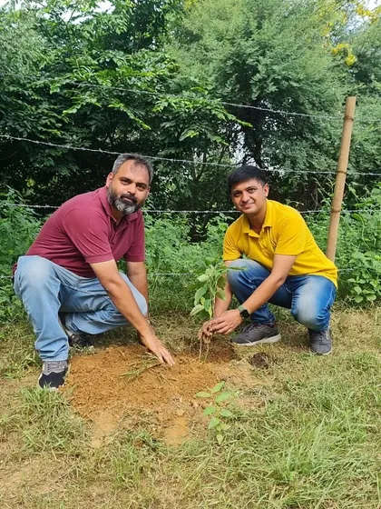 Two volunteers from NatWest plant a sapling together, part of a larger effort to bring back the native ecosystem of the Ghata Bundh.