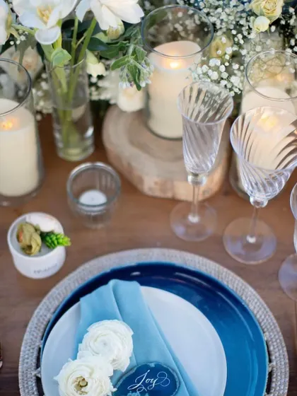 A close-up of an elegant table setting. The details matter, from the layered plates and custom place cards to the choice of glassware and floral accents.