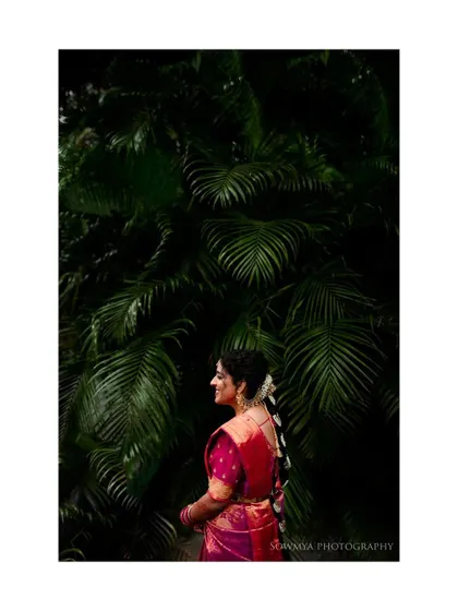 A beautiful bridal portrait against a backdrop of lush palm leaves. The contrast between her pink saree and the deep green is stunning.