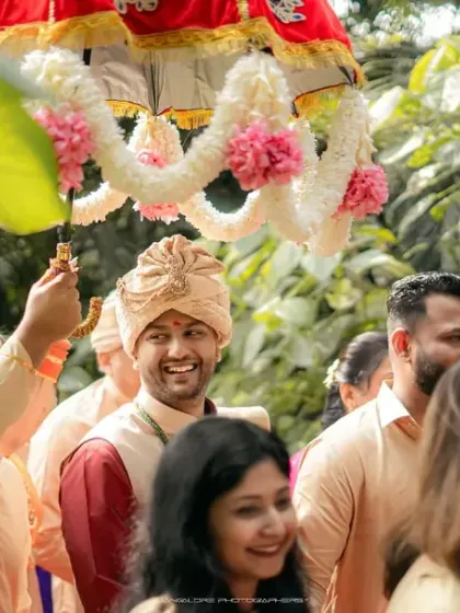 The groom's happy entrance under a traditional decorated umbrella. His smile shows the excitement and joy of the moment.