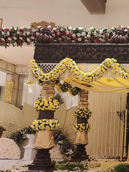 A side view of the traditional mandap, showing the detailed carving on the upper frame and the thick floral runners made of red and white roses.