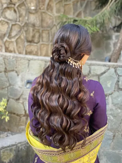A lovely half-up bun with flowing waves to complete her mehendi look. This style is both practical and beautiful, keeping hair away from the face while showing off length.