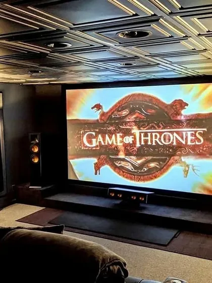 An example of a truly immersive themed environment, this home cinema features a massive projection screen perfect for epic series like Game of Thrones. The design incorporates a decorative coffered ceiling and strategically placed tower speakers to create a powerful, enveloping soundstage that transports you directly into the story.