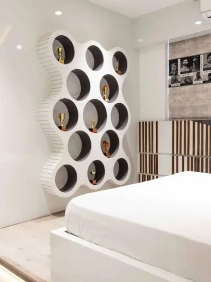 A unique, custom-designed display unit with circular niches adds a playful and artistic element to this bedroom. It serves as a personalized showcase for collectibles while acting as a sculptural piece.