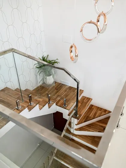 This shot highlights the wooden staircase with a glass railing, which adds a modern touch while keeping the space feeling open. The hanging ring lights add a sculptural, artistic element.