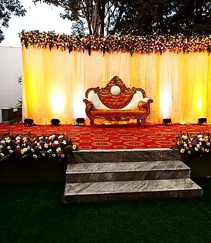 A simple and elegant floral decor for a dhoti ceremony. The outdoor stage setup features a warm yellow backdrop and beautiful floral arrangements, perfect for this traditional milestone.