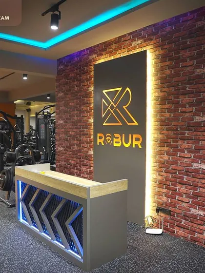 To enhance the gym's energetic vibe, we created a dedicated DJ area. The design incorporates an industrial-style brick accent wall and a backlit brand logo, creating a focal point that energizes the entire workout floor.