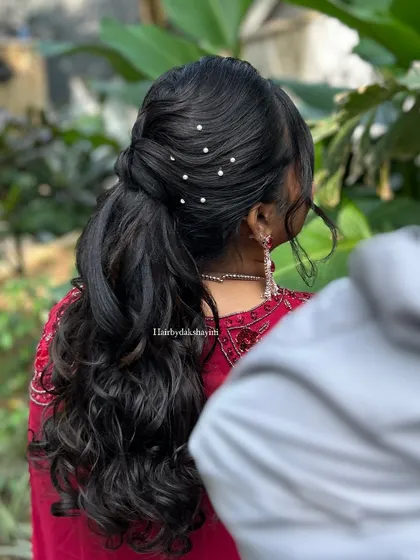 A back view of the curly ponytail, showing the neat twist detail and pearl accents.