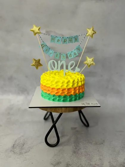 A colorful and festive cake to celebrate a first birthday. The bright textured buttercream and starry banner make it a happy centerpiece.