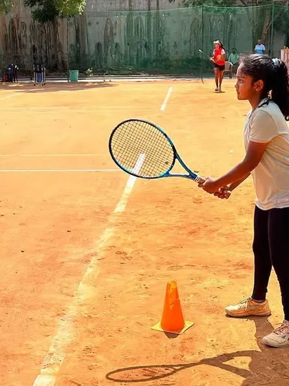 A young player practicing her ready position at the baseline. Our coaching focuses on fundamentals, ensuring every player has a solid technical base.