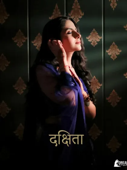 A stunning portrait of bride-to-be Dakshita, bathed in warm light that highlights her royal blue outfit and serene expression.