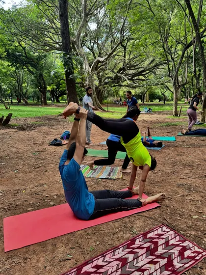 A moment of connection and trust during a partner yoga session in a park. This AcroYoga pose demonstrates the playful and community-oriented side of our practice, building strength and balance together.