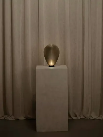 A single bronze glass Solace lamp creates an intimate and moody atmosphere, its form almost disappearing into the shadows until illuminated.