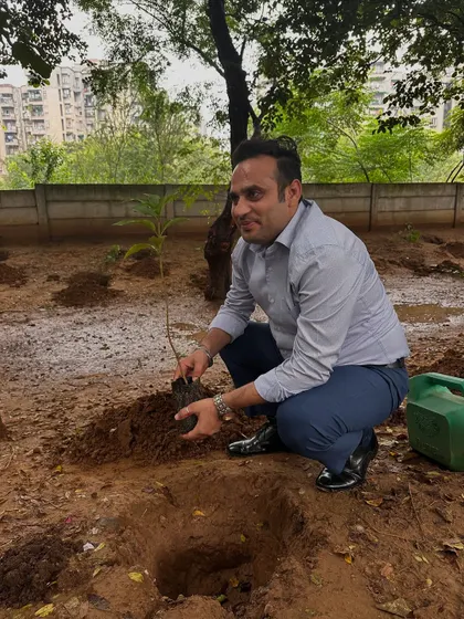 A volunteer from Calpro Specialities carefully prepares to plant a native sapling, contributing to the restoration of Aravali Creek.