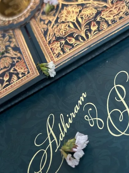 A close-up of the elegant gold script and subtle embossed pattern on the deep blue invitation.