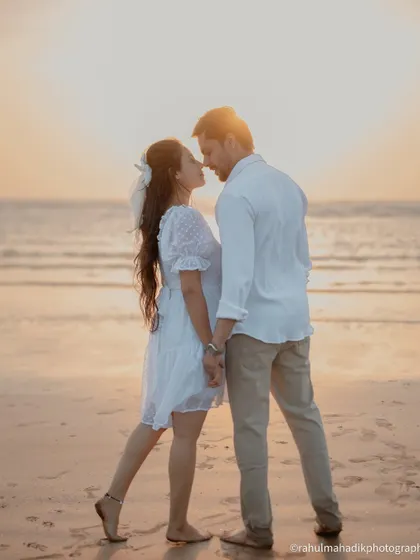 A classic sunset silhouette on the beach. The couple is about to kiss, framed against the glowing sky and sea. This is a timeless and romantic shot for any pre-wedding gallery.