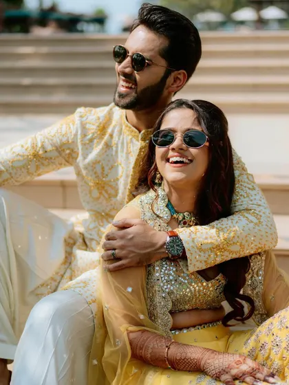 A close-up candid of the couple enjoying a sunny day in Goa, their smiles and sunglasses reflecting the happy, relaxed atmosphere.