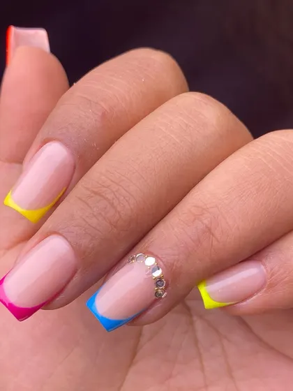 A fun and modern take on the French manicure with multi-colored neon tips and a line of rhinestones at the cuticle.