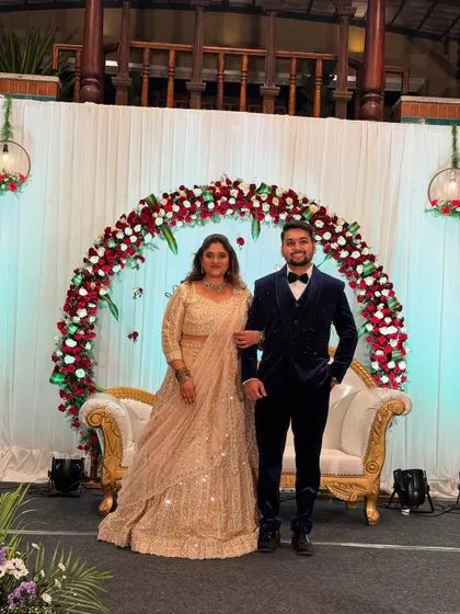 A beautiful couple posing on their engagement stage. The floral arch and classic sofa create a perfect photo opportunity.