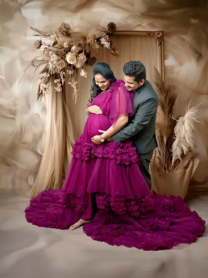 Another tender moment, with the partner gently holding the baby bump. The soft lighting and romantic styling make this a truly special portrait for the expecting couple.