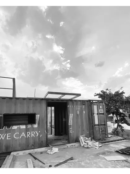 A view of the container with openings cut out and the beginnings of a roof structure. The original "WE CARRY" text is still visible, hinting at its past life.